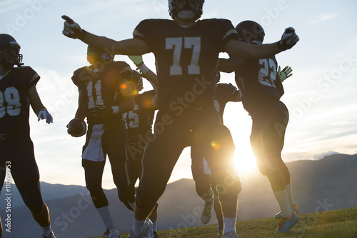 Silhouetted male american football team celebrating at sunset photo