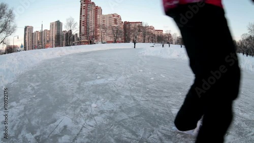 Young Caucasian girl skating on frozen ice of urban pond. Wide angle view. Winter is in Russia
