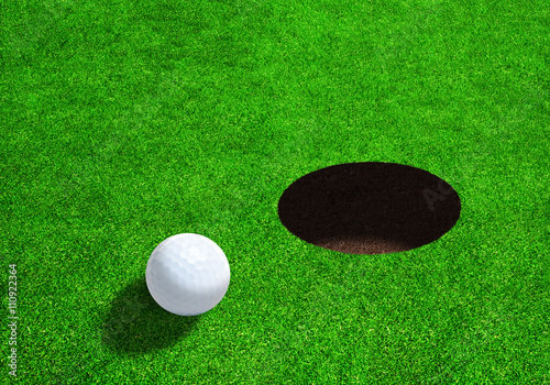 Golf Ball Close to Hole With Copy Space. Low side angle view.