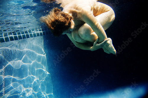 Mature woman, nude, in foetal position, underwater view photo