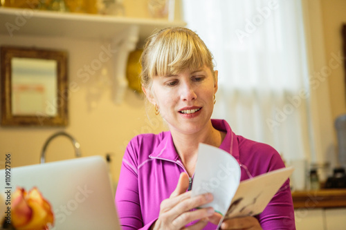 Woman working in kitchen table reading instruction booklet photo