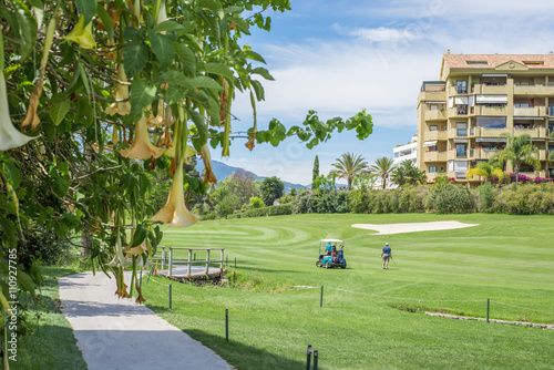 Golf course flowers with people playing.