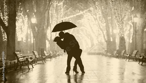 Couple with umbrella kissing at night alley. photo