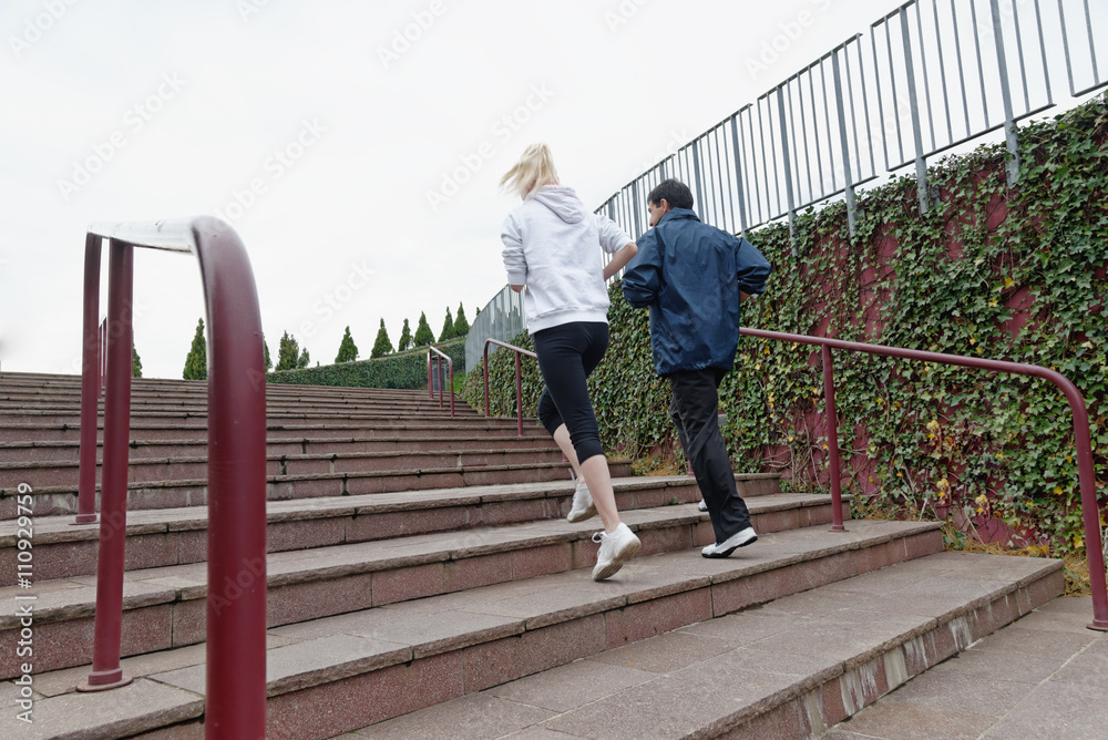 Man and woman running up steps together, rear view Man and woman running up steps together, rear view