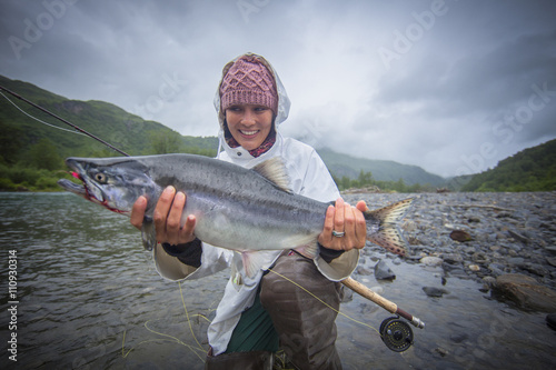 Fisherwoman holding up caught pink salmon in river, Kodiak, Alaska, USA photo