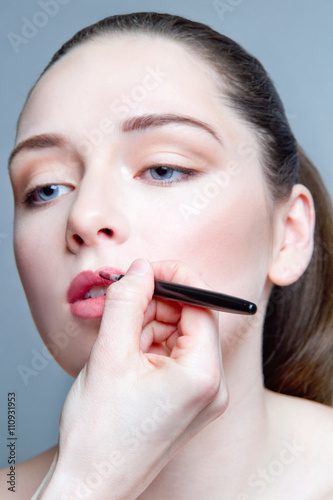 Young woman having lip liner applied to lips