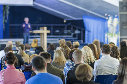 Male Lecturer Speaking In front of the Team Group sitting in Large Hall