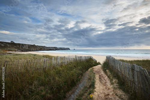 Fotografering Sandy footpath leading to ocean coastline through green grass Pointe de Toulingu
