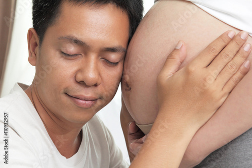 Face of young Asians are happy with the listening sound of children in the womb of his wife