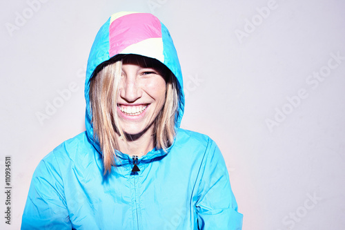 Studio portrait of young woman wearing turquoise hooded anorak