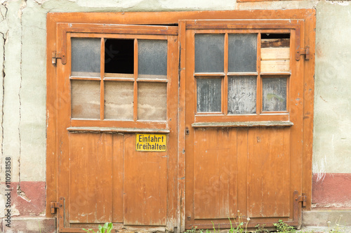 Old barn door with broken glass and sign     German Translation    Keep entrance free     