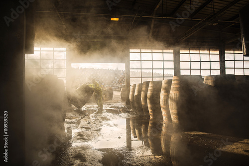 Worker pushing barrel in warehouse photo