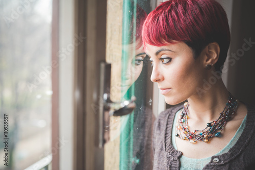 Young woman looking out of window, pensive expression