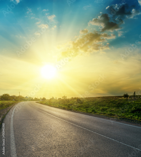 bright sunset in clouds over asphalt road