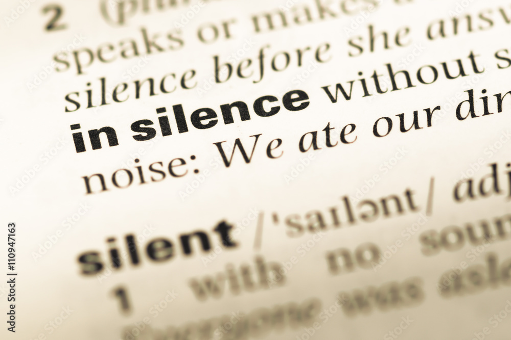 Close up of old English dictionary page with word in silence Close up of old English dictionary page with word in silence