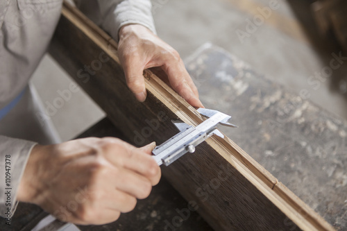 Carpenter measuring wood plank with vernier caliper in factory, Jiangsu, China photo