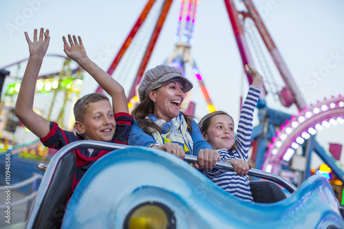 Mature woman with son and daughter on fairground ride