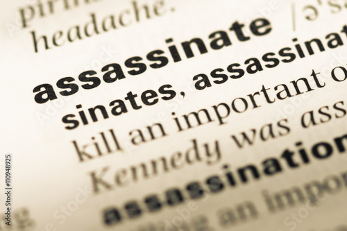 Close up of old English dictionary page with word assassinate