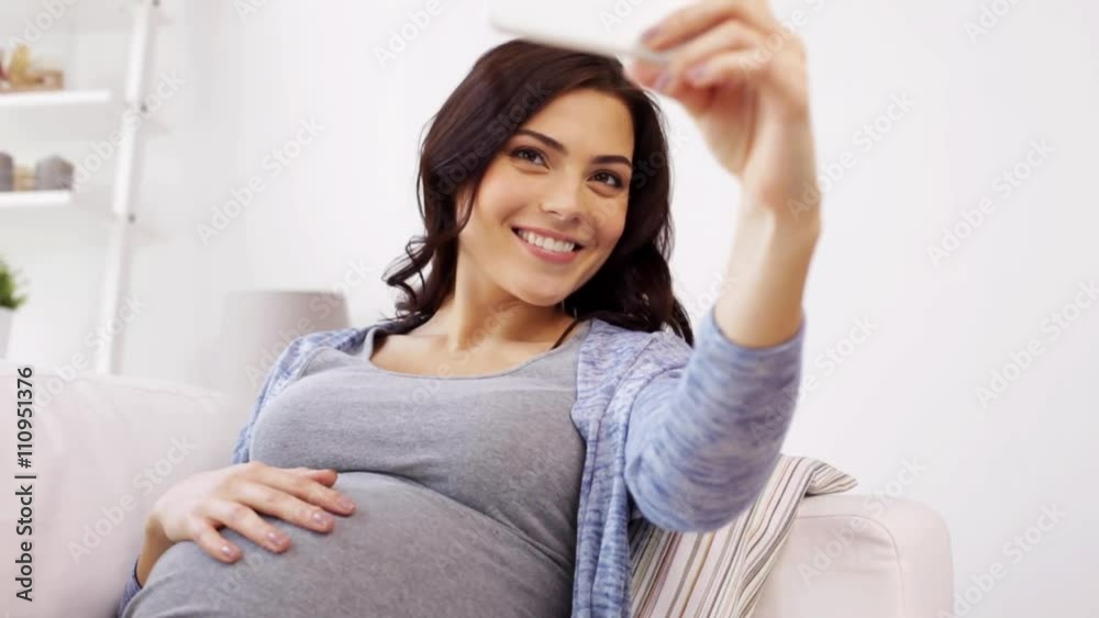 pregnant woman taking selfy by smartphone at home pregnant woman taking selfy by smartphone at home