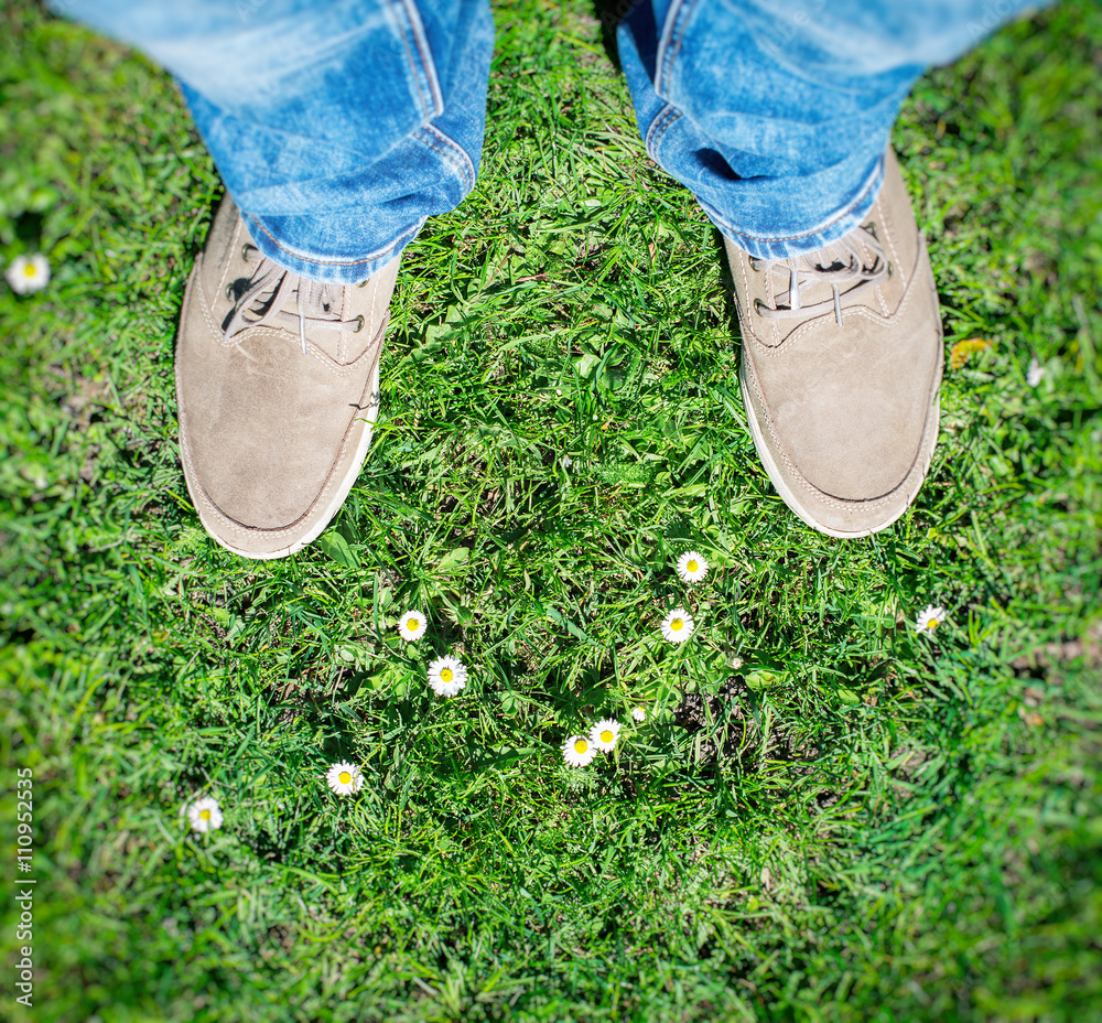 Summer is coming! Male boots on the grass with first flowers. Top view. Summer is coming! Male boots on the grass with first flowers. Top view.