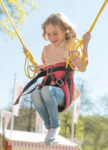 Fotografie Little girl on bungee trampoline with cords.