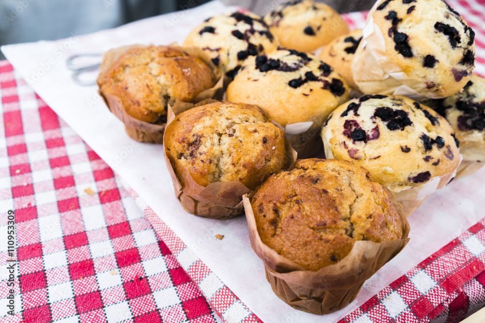 Fresh baked muffins on a red checked cloth in a market in Paris, France