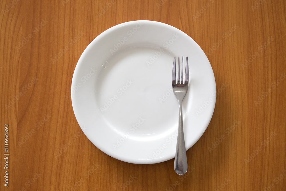 white circle ceramic dish with silver fork on wood table white circle ceramic dish with silver fork on wood table