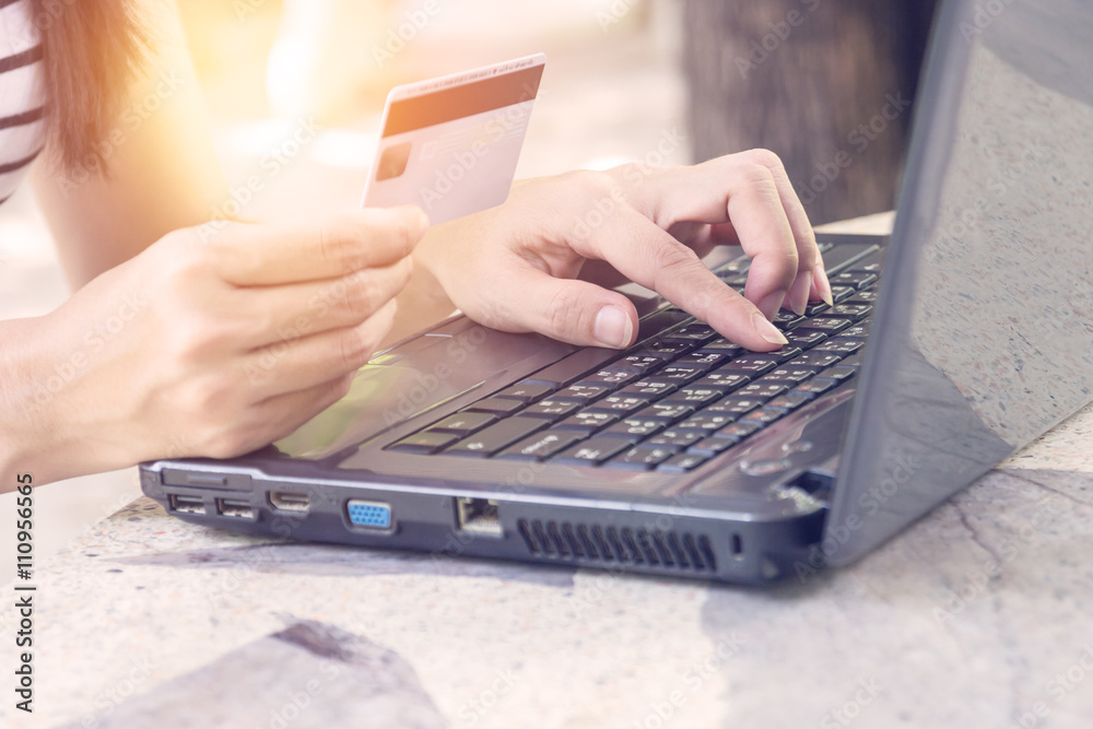 Hands holding credit card and using laptop.