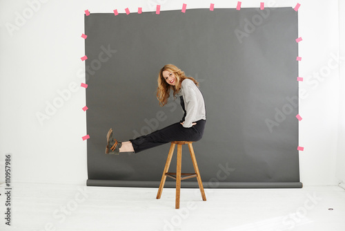 Woman on stool in front of photographers backdrop photo