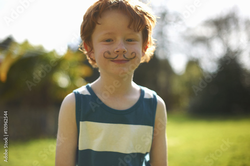Portrait of young boy with drawn on moustache
