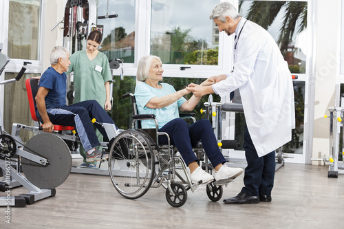 Doctor Holding Senior Woman's Hands In Wheelchair