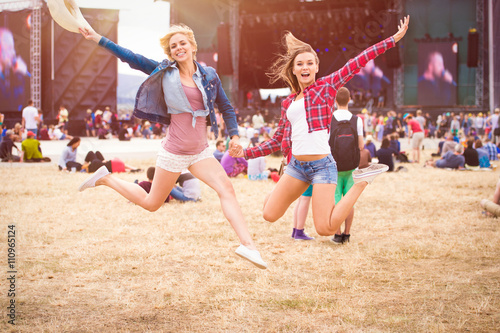 Teenage girls, music festival, jumping, in front of stage photo