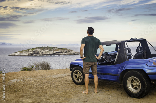 Rear view of male tourist looking out to Branca island, Buzios, Rio de Janeiro, Brazil photo