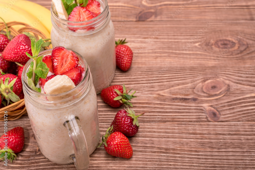 Smoothies with oatmeal ,strawberry, banana in glass jars on a wooden background. Smoothies with oatmeal ,strawberry, banana in glass jars on a wooden background.