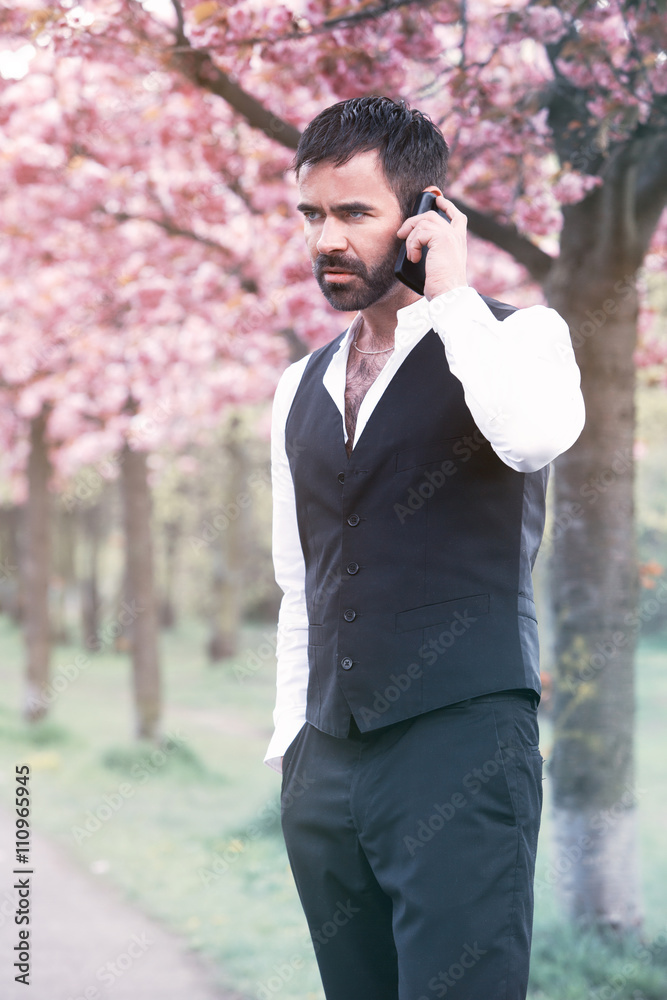 businessman standing in park and talking on phone