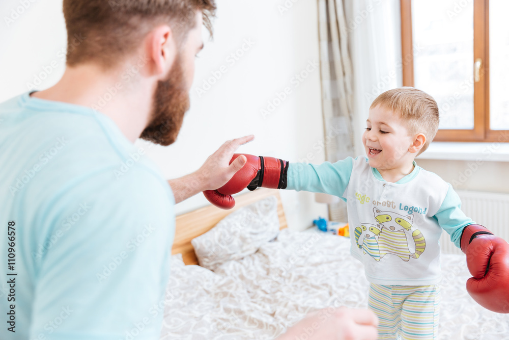 Father playing with his son in boxing gloves at home Father playing with his son in boxing gloves at home