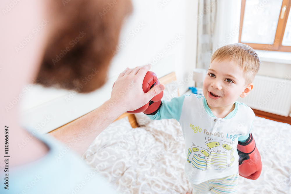 Little boy playing with his father using boxing gloves