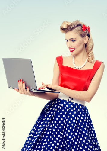 woman holding laptop, dressed in pin-up style dress