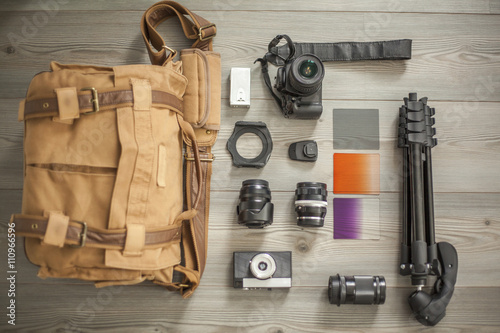 Camera equipment and camera bag arranged on table, overhead view