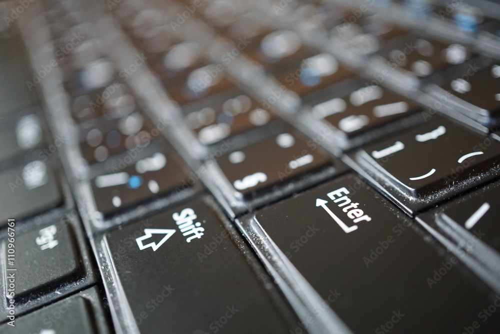Detail of a black dusty laptop keyboard with a focus on an Enter key Detail of a black dusty laptop keyboard with a focus on an Enter key