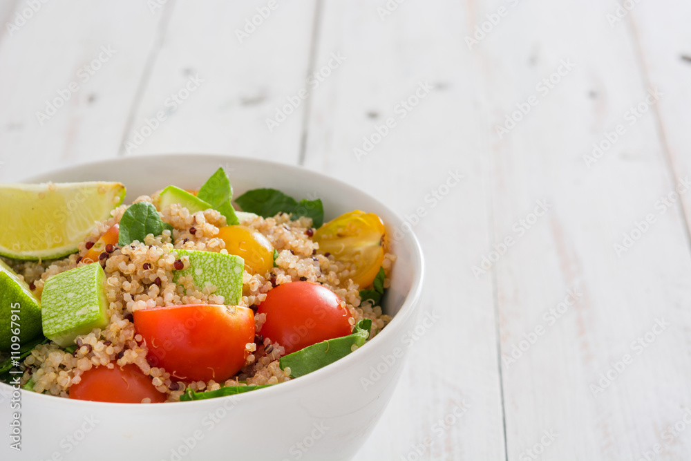 Quinoa salad in bowl, tomatoes and spinach on white wooden table
Quinoa salad in bowl, tomatoes and spinach on white wooden table
