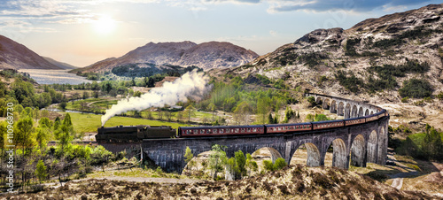 Photo Glenfinnan Railway Viaduct in Scotland with the Jacobite steam train against sun