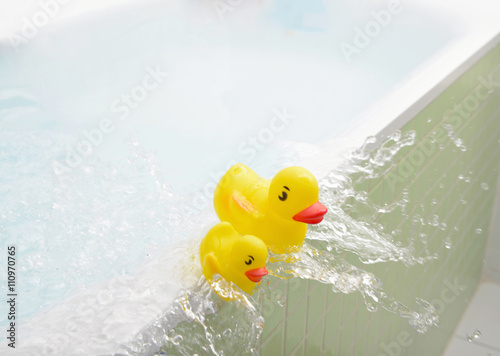 Rubber ducks falling out of bath overflowing with water
