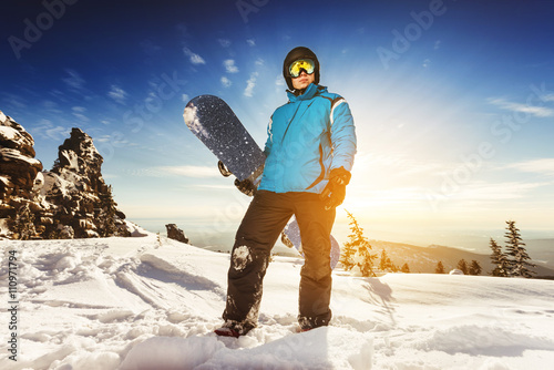 Snowboarder stands with snowboard in sunset light. Sheregesh resort, Siberia, Russia photo