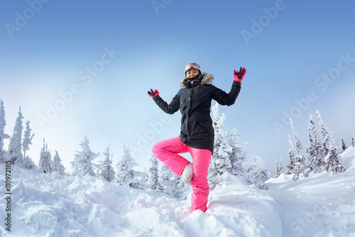 Snowboarder girl stands in yoga pose in snowbound forest. Sheregesh resort, Siberia, Russia