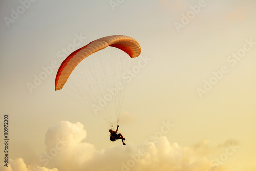 Paraglider flies on clouds backdrop