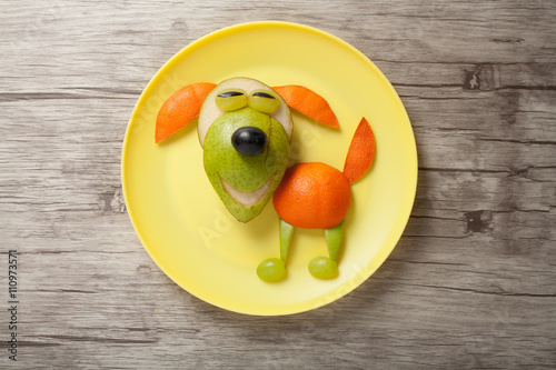 Dog made of juicy fruits on plate