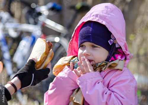 Маленькая девочка отказывается от жареной сосиски в хлебе на природе