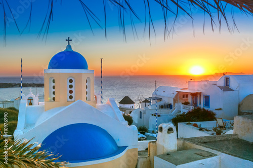 Picturesque view, Old Town of Oia or Ia on the island Santorini, white houses and church with blue domes at sunset, Greece