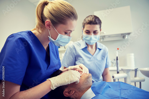 female dentist checking patient dental occlusion